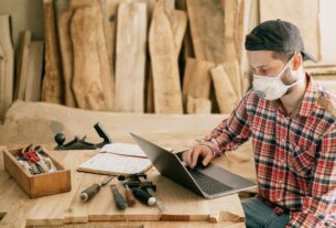 man using a laptop at a wood workshop